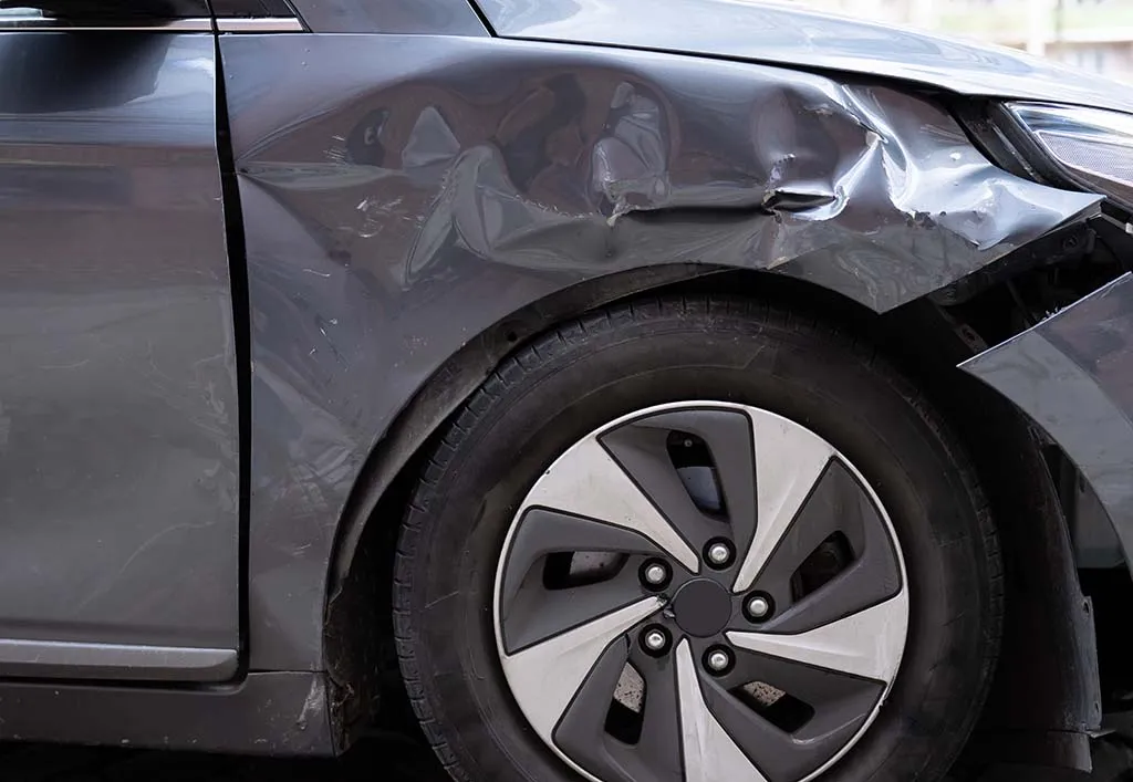 A vehicle with collision damage to the front fender and bumper before repair